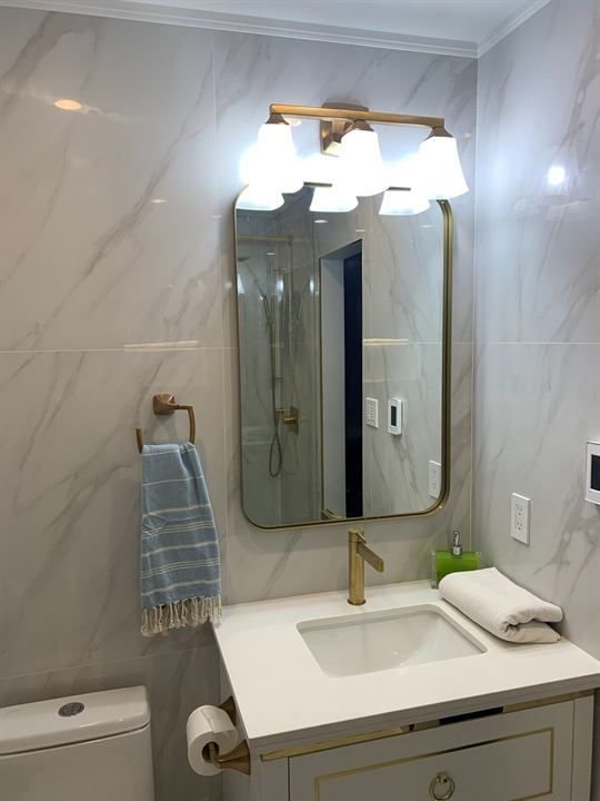 Vanity with brushed gold accents, mirror and lighting