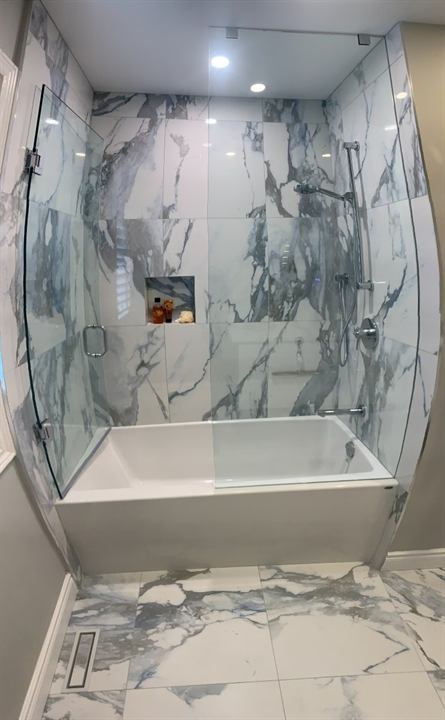 Tub and shower with large-format marble-look porcelain and curved glass