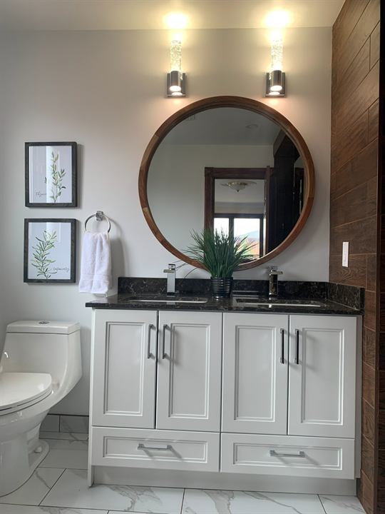 Bathroom vanity with quartz top, round mirror and wall sconces