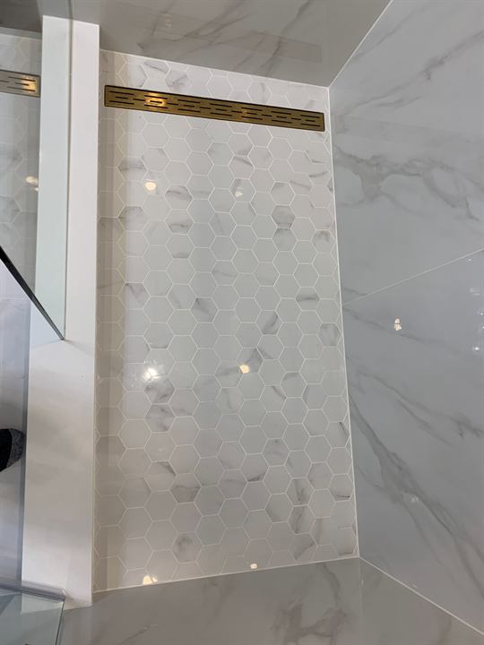 Hexagon mosaic shower floor with gold linear drain